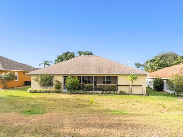 rear view of house featuring a lawn, an attached garage, and stucco siding
