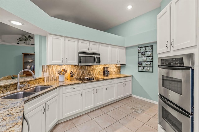kitchen with white cabinets, light tile patterned flooring, appliances with stainless steel finishes, a sink, and backsplash