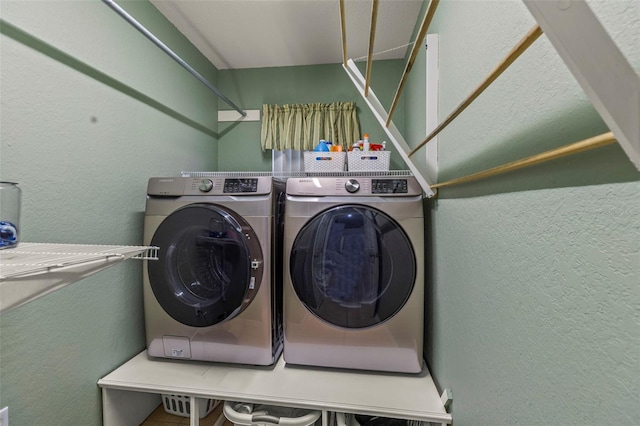 washroom featuring separate washer and dryer, a textured wall, and laundry area