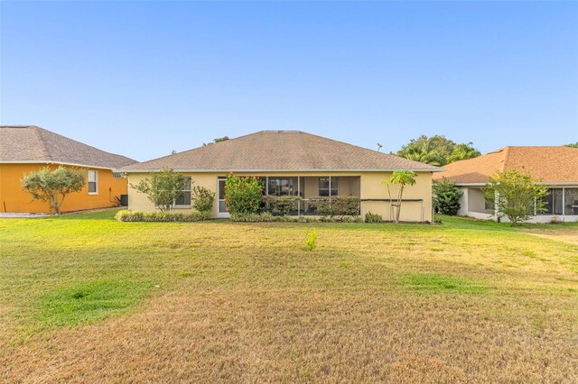 rear view of property with a lawn and stucco siding