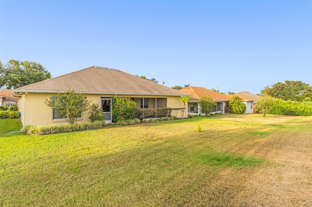 back of property featuring stucco siding and a yard