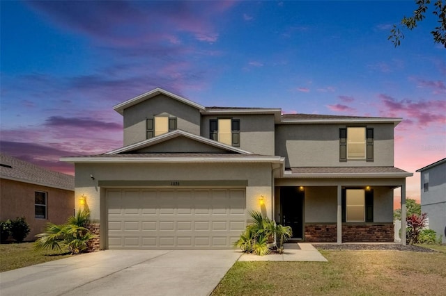 traditional home with stucco siding, driveway, stone siding, an attached garage, and a lawn