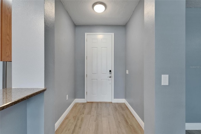 doorway to outside featuring light wood-style flooring and baseboards