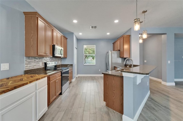 kitchen with baseboards, light wood-style floors, visible vents, decorative backsplash, and stainless steel appliances