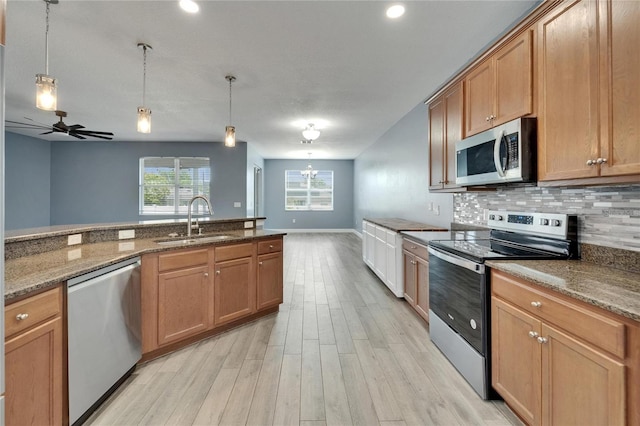 kitchen with light wood-style flooring, a ceiling fan, a sink, stainless steel appliances, and decorative backsplash