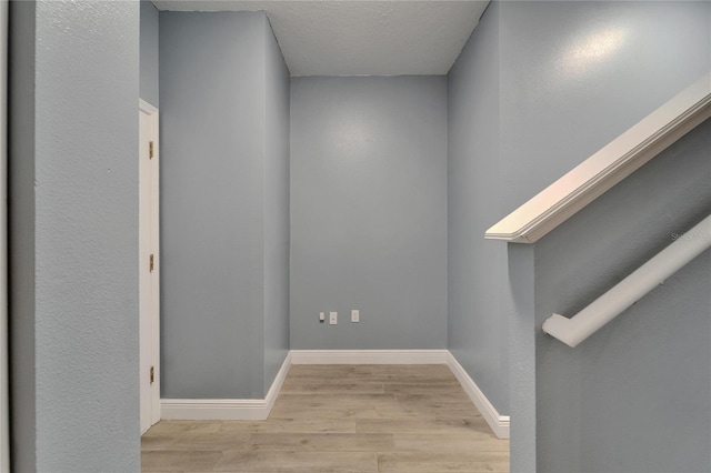 interior space with baseboards, a textured ceiling, and wood finished floors