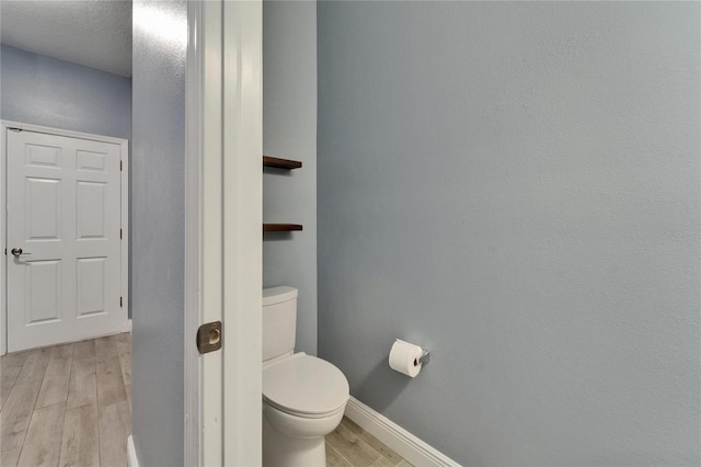bathroom featuring toilet, wood finished floors, and baseboards