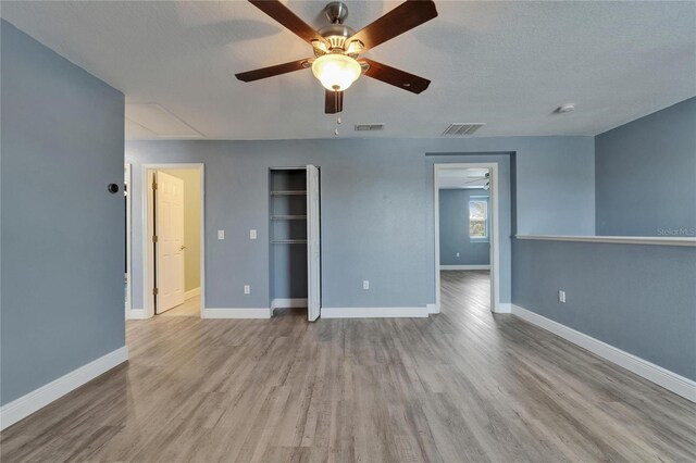 unfurnished bedroom with wood finished floors, attic access, baseboards, and visible vents