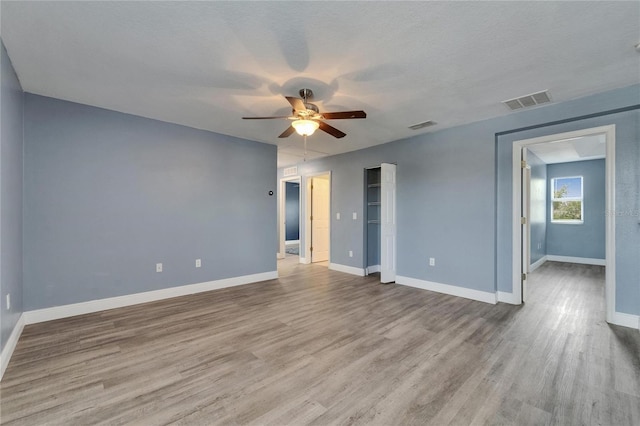 interior space featuring wood finished floors, ceiling fan, baseboards, and visible vents