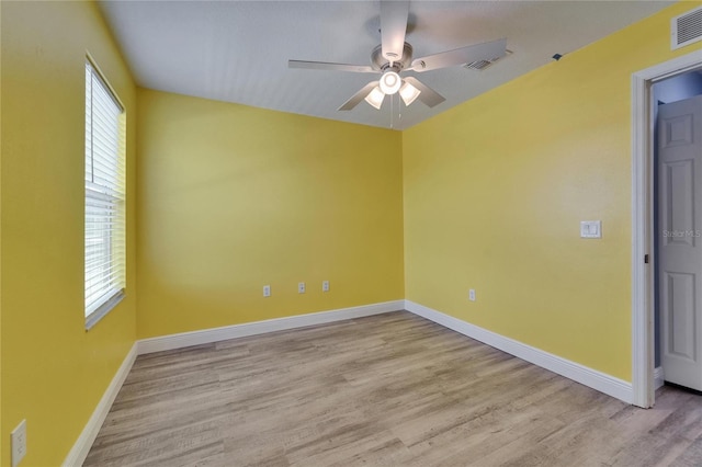 unfurnished room featuring light wood finished floors, visible vents, baseboards, and a ceiling fan