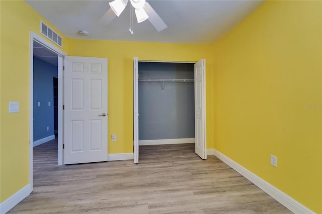 unfurnished bedroom with a closet, a ceiling fan, visible vents, wood finished floors, and baseboards