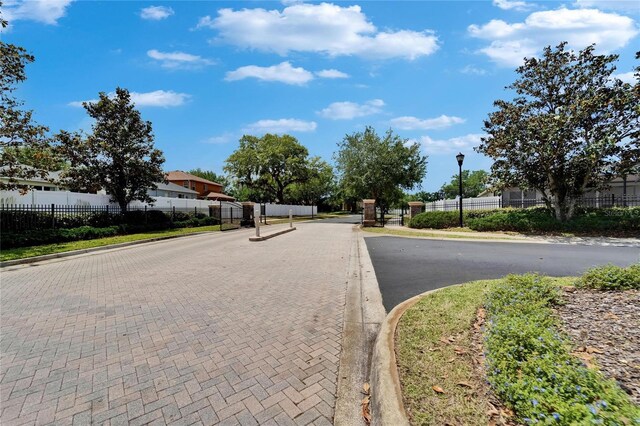 view of road featuring street lighting, a gated entry, and curbs