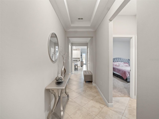 corridor featuring visible vents, ornamental molding, baseboards, and light tile patterned flooring