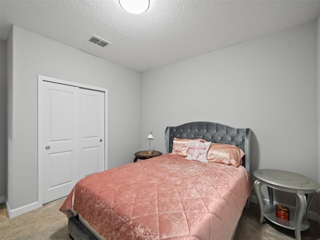 bedroom with carpet floors, baseboards, a textured ceiling, and visible vents