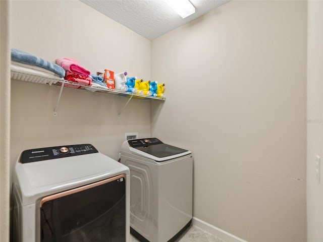 laundry room with baseboards, laundry area, a textured ceiling, and washing machine and clothes dryer