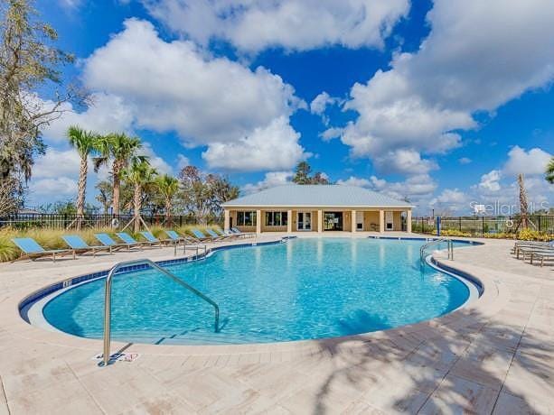 community pool with a patio area and fence