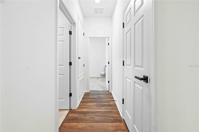 hall featuring dark wood-style floors and visible vents