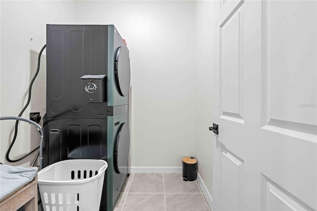 washroom with stacked washer and dryer, laundry area, baseboards, and light tile patterned floors
