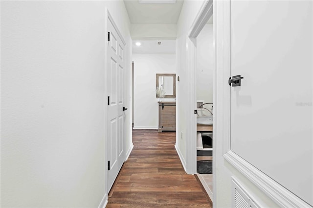 hallway with dark wood-style flooring and baseboards