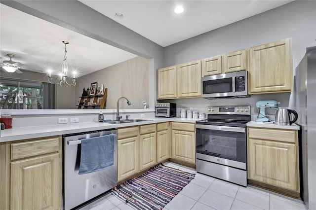 kitchen with stainless steel appliances, light countertops, a sink, and light brown cabinetry