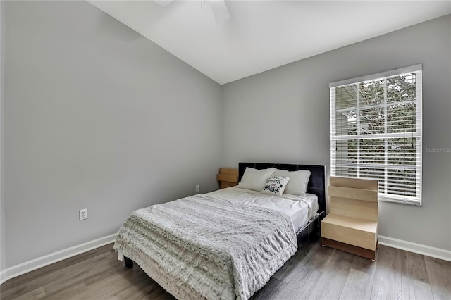 bedroom featuring wood finished floors, ceiling fan, baseboards, and lofted ceiling
