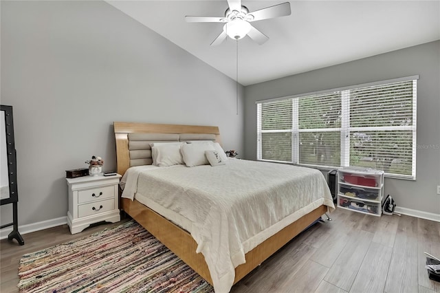 bedroom featuring baseboards, wood finished floors, vaulted ceiling, and a ceiling fan