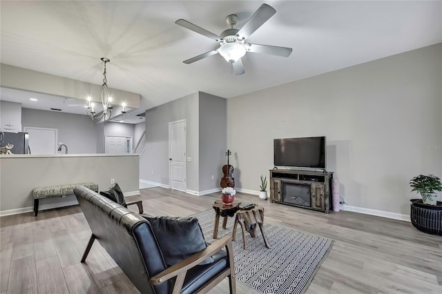 living room with baseboards, ceiling fan with notable chandelier, and wood finished floors