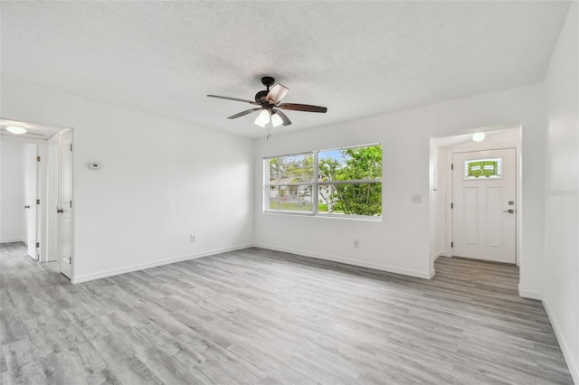 2401 Havana Dr, Clearwater, FL 33764 - unfurnished living room with a textured ceiling, baseboards, light wood-type flooring, and a ceiling fan