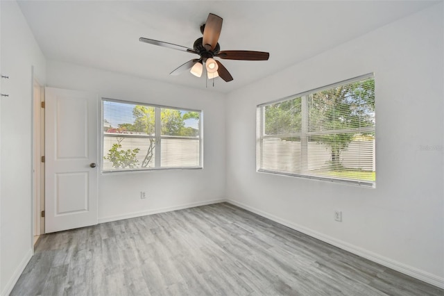 2401 Havana Dr, Clearwater, FL 33764 - empty room with a wealth of natural light, a ceiling fan, wood finished floors, and baseboards