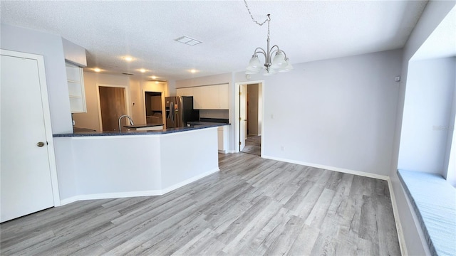 kitchen with light wood-style floors, stainless steel fridge with ice dispenser, a textured ceiling, white cabinetry, and a chandelier