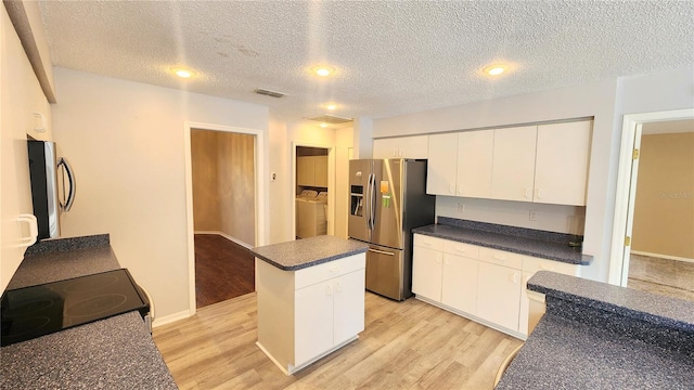 kitchen featuring light wood-style flooring, dark countertops, fridge, and stainless steel refrigerator with ice dispenser