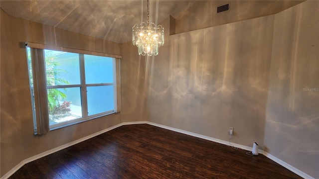 unfurnished room featuring a wealth of natural light, a notable chandelier, dark wood-type flooring, and visible vents