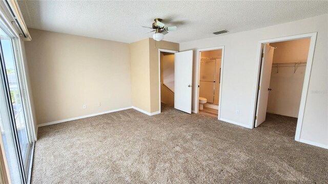 unfurnished bedroom featuring visible vents, a closet, baseboards, a spacious closet, and carpet