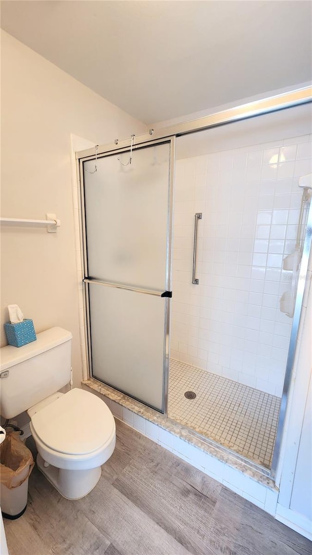 full bath featuring a stall shower, toilet, and wood finished floors