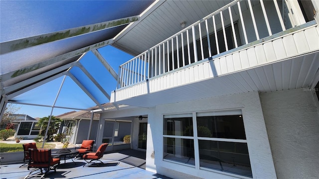 view of patio featuring a balcony and glass enclosure