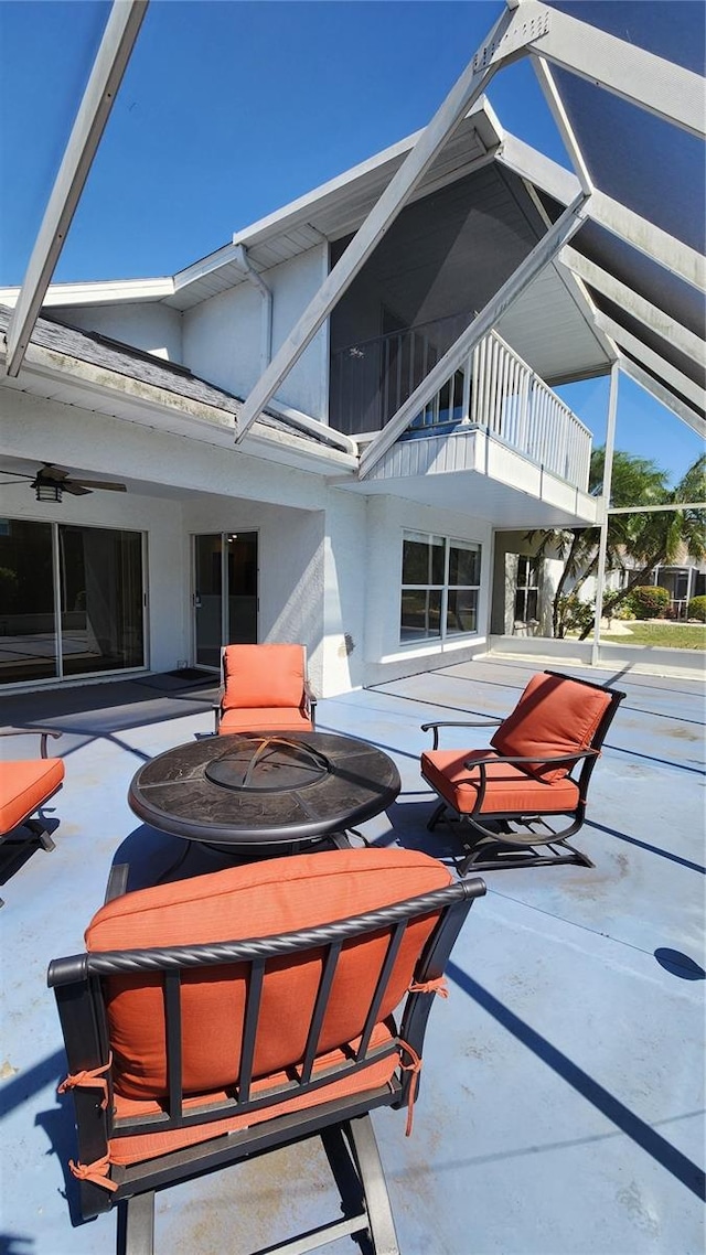 exterior space featuring a patio area, ceiling fan, stucco siding, a balcony, and a lanai