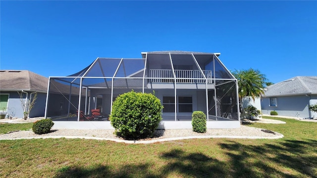 back of property featuring glass enclosure, a lawn, and stucco siding