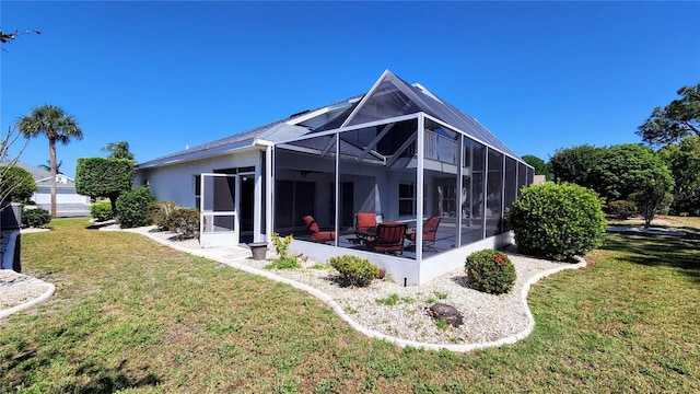 back of property with a yard, glass enclosure, and stucco siding