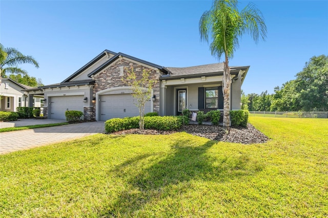 19325 Hawk Valley Dr, Tampa, FL 33647 - craftsman house featuring stone siding, decorative driveway, fence, a front lawn, and a garage