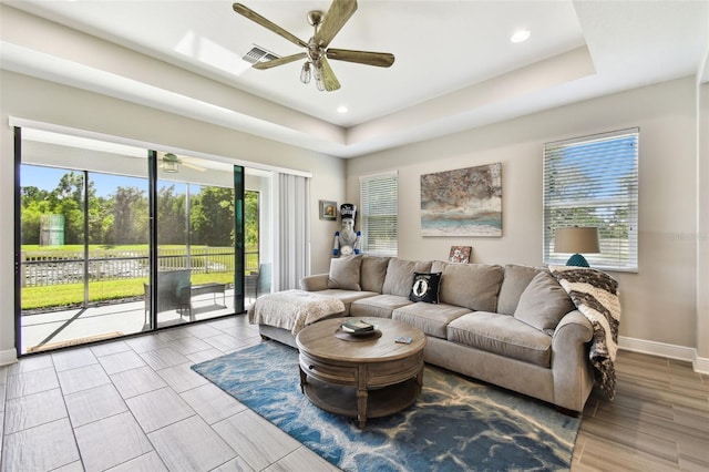 19325 Hawk Valley Dr, Tampa, FL 33647 - living room with a raised ceiling, ceiling fan, plenty of natural light, and visible vents