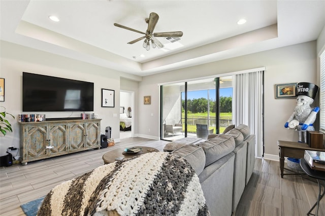 19325 Hawk Valley Dr, Tampa, FL 33647 - living room featuring wood tiled floor, a raised ceiling, a ceiling fan, and baseboards