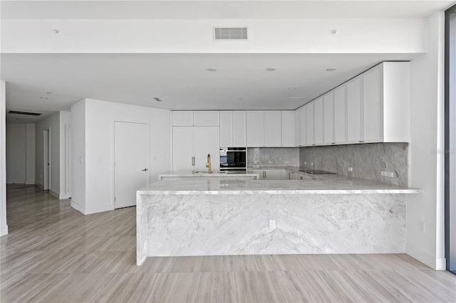2912 W Santiago St Unit 1401, Tampa, FL 33629 - kitchen featuring a sink, white cabinetry, a peninsula, tasteful backsplash, and visible vents