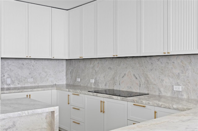 2912 W Santiago St Unit 1401, Tampa, FL 33629 - kitchen featuring light stone counters, backsplash, white cabinetry, and black electric cooktop