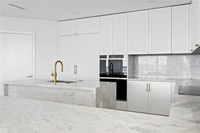 2912 W Santiago St Unit 1401, Tampa, FL 33629 - kitchen featuring visible vents, tasteful backsplash, light stone countertops, a sink, and white cabinetry