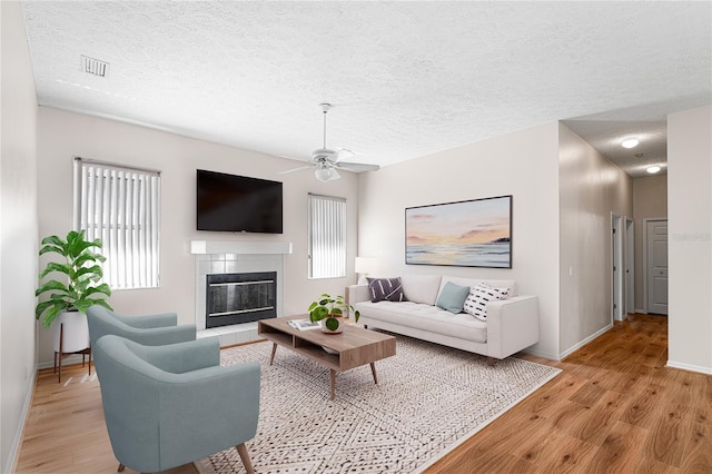 2803 Bent Leaf Dr, Valrico, FL 33594 - living room with light wood finished floors, baseboards, a tile fireplace, a ceiling fan, and a textured ceiling