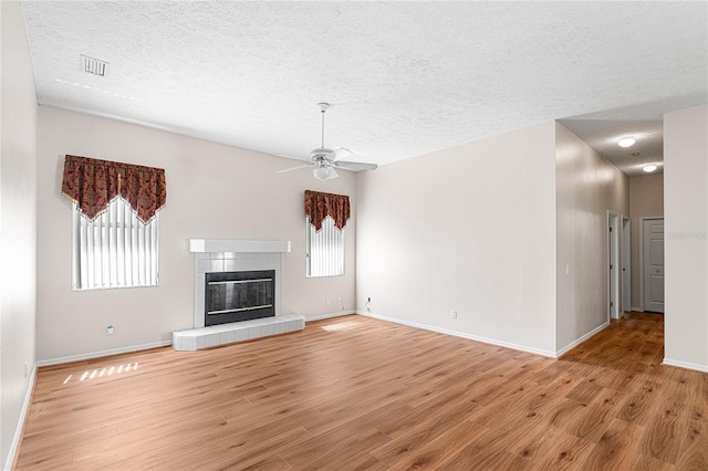 2803 Bent Leaf Dr, Valrico, FL 33594 - unfurnished living room with a textured ceiling, light wood finished floors, ceiling fan, baseboards, and a tile fireplace
