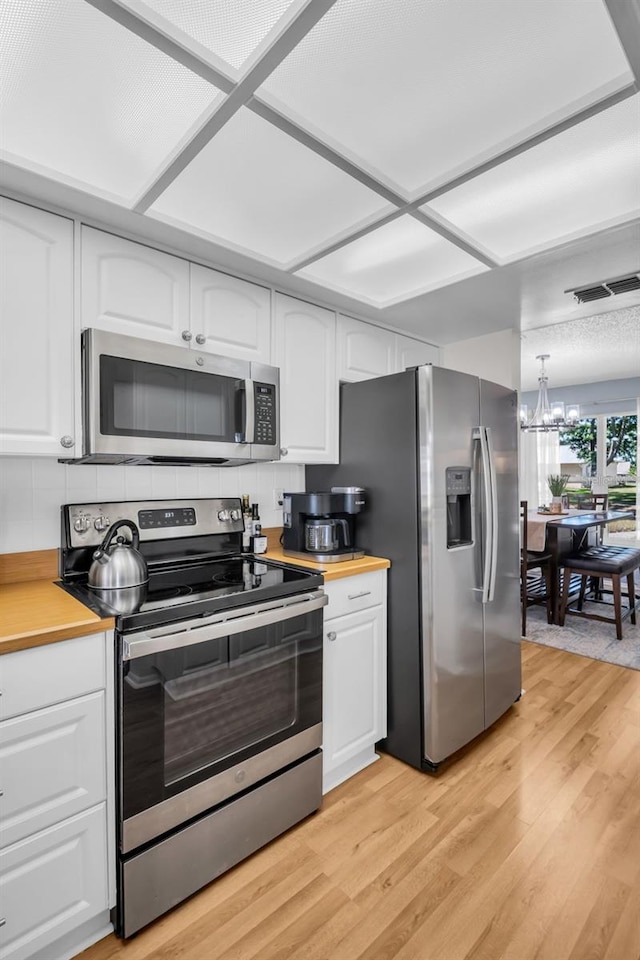 1657 Glengarry Dr, Palm Harbor, FL 34684 - kitchen with white cabinetry, appliances with stainless steel finishes, light wood-style flooring, and visible vents