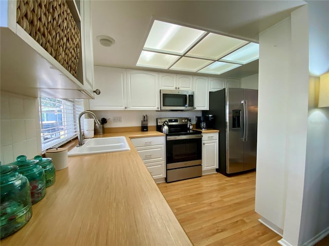 1657 Glengarry Dr, Palm Harbor, FL 34684 - kitchen with a sink, light countertops, white cabinets, stainless steel appliances, and light wood-style flooring