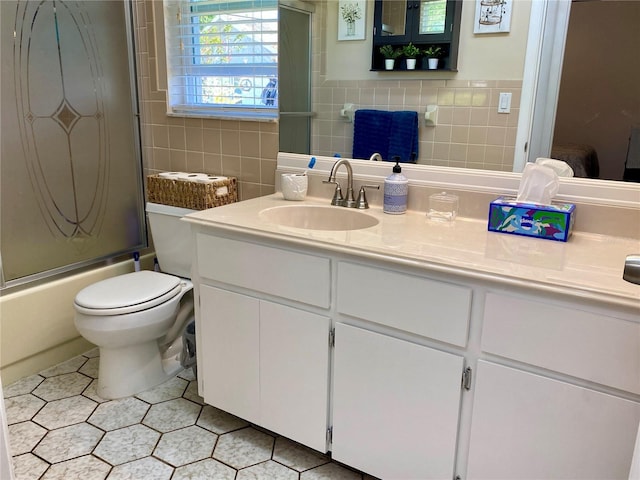 1657 Glengarry Dr, Palm Harbor, FL 34684 - full bath with vanity, toilet, tile walls, bath / shower combo with glass door, and tile patterned floors
