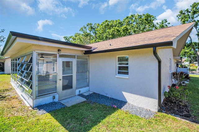 1657 Glengarry Dr, Palm Harbor, FL 34684 - rear view of house featuring a sunroom, a lawn, stucco siding, and roof with shingles